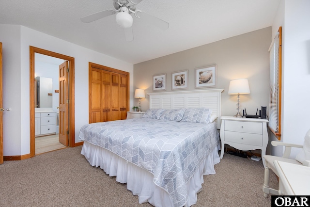 bedroom featuring a closet, light colored carpet, ensuite bathroom, a ceiling fan, and baseboards