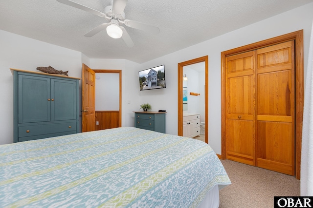 bedroom featuring a ceiling fan, light colored carpet, a textured ceiling, and ensuite bathroom