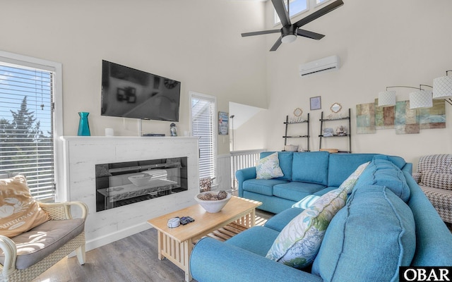 living area featuring a wall mounted air conditioner, wood finished floors, and a healthy amount of sunlight