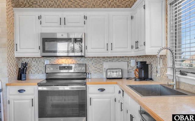 kitchen with appliances with stainless steel finishes, white cabinets, and light countertops