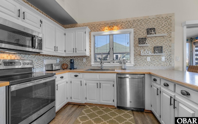 kitchen with dark wood finished floors, stainless steel appliances, light countertops, white cabinets, and a sink