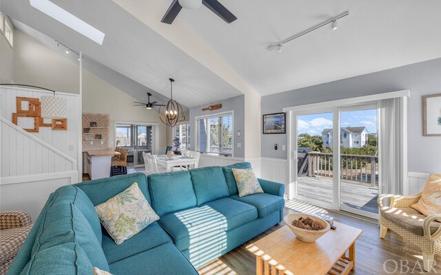 25056 Sea Vista Ct Lot 29, Waves, NC 27982 - living area featuring vaulted ceiling with skylight, wainscoting, wood finished floors, track lighting, and ceiling fan with notable chandelier
