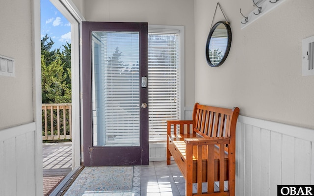 doorway to outside featuring french doors, a wainscoted wall, plenty of natural light, and light tile patterned floors