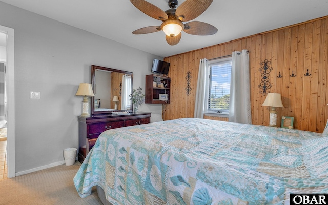 bedroom with baseboards, wooden walls, ceiling fan, and light colored carpet