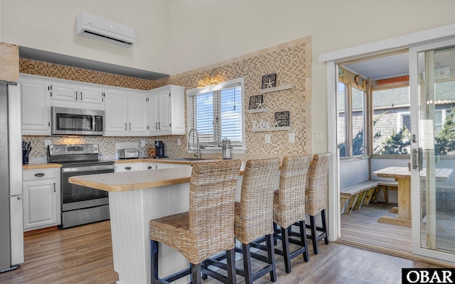 kitchen with stainless steel appliances, a peninsula, a kitchen bar, and light countertops