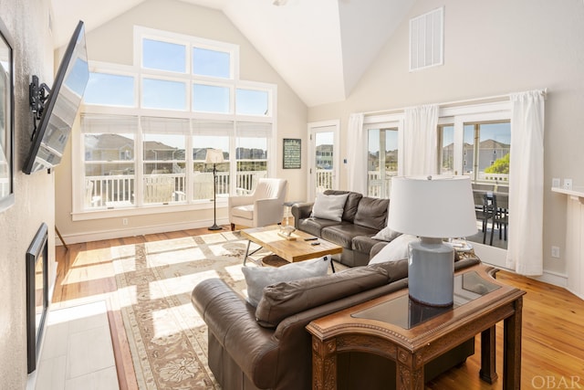 living area with light wood-type flooring, high vaulted ceiling, and visible vents