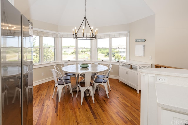 dining space featuring vaulted ceiling, wood finished floors, and a chandelier