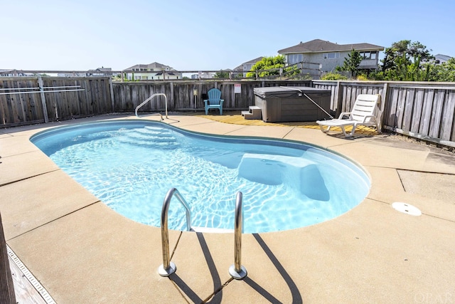 view of swimming pool with a hot tub, a fenced in pool, a fenced backyard, a residential view, and a patio area