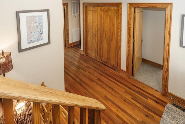 hall featuring dark wood finished floors, visible vents, and baseboards