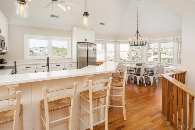 kitchen with visible vents, appliances with stainless steel finishes, a breakfast bar, light countertops, and white cabinetry