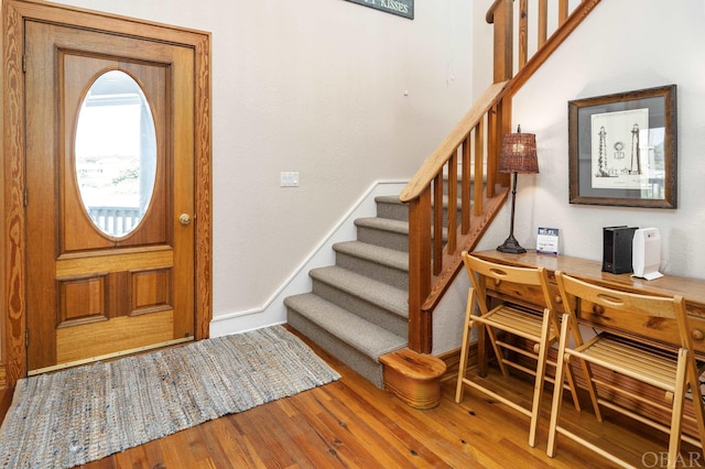 foyer featuring stairs, baseboards, and wood finished floors