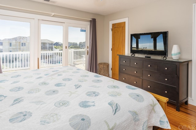 bedroom with access to exterior, visible vents, and light wood-style floors