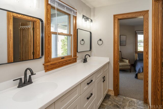 bathroom featuring ensuite bath, plenty of natural light, and a sink