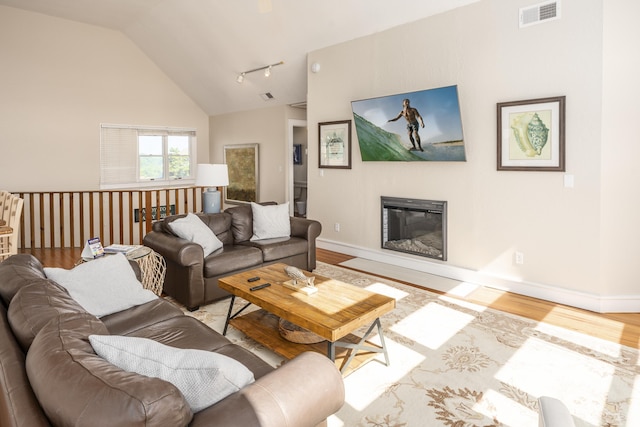 living room with light wood finished floors, baseboards, visible vents, and a glass covered fireplace