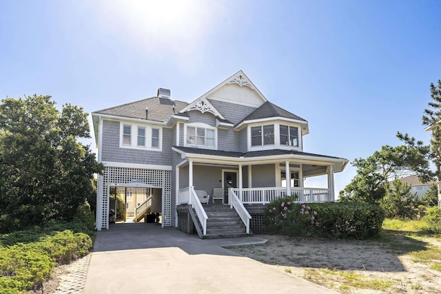 victorian house with covered porch, driveway, a carport, and stairway