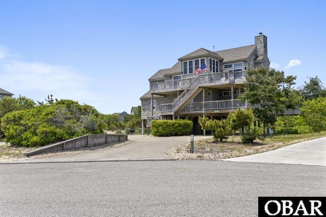 beach home with a chimney, driveway, and a balcony