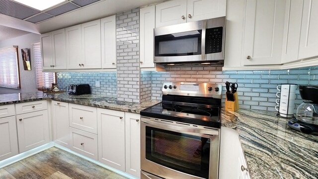 kitchen with dark stone counters, appliances with stainless steel finishes, and white cabinets