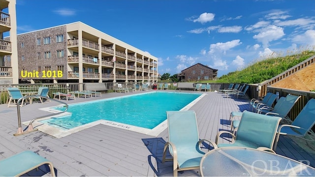 community pool featuring fence and a wooden deck