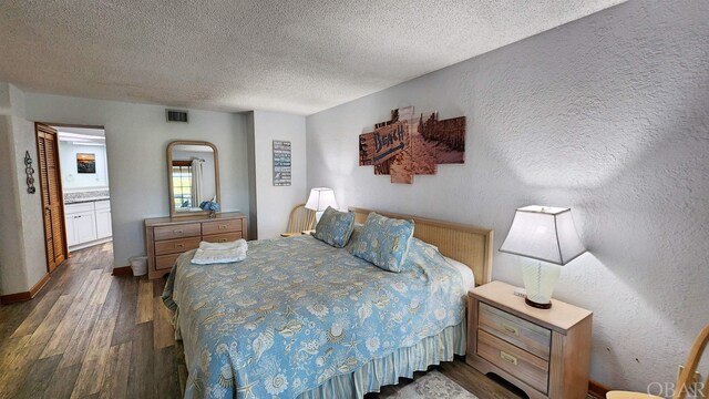 bedroom featuring dark wood finished floors, visible vents, a textured wall, a textured ceiling, and baseboards