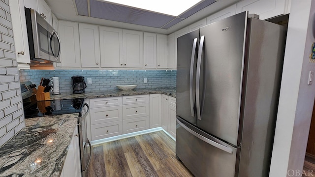 kitchen featuring dark stone counters, stainless steel appliances, and white cabinets