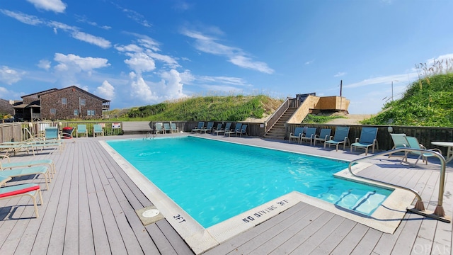 community pool with a patio, stairway, and fence