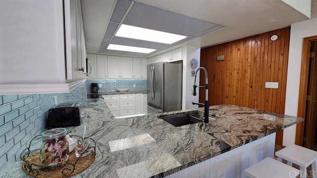 kitchen with white cabinets, a kitchen breakfast bar, a peninsula, stainless steel appliances, and a sink