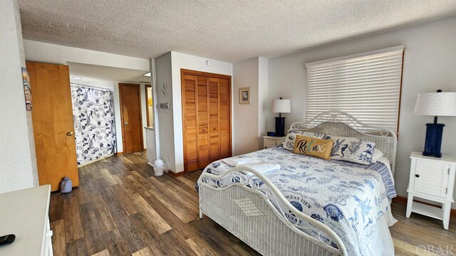 bedroom with a closet, dark wood finished floors, a textured ceiling, and baseboards