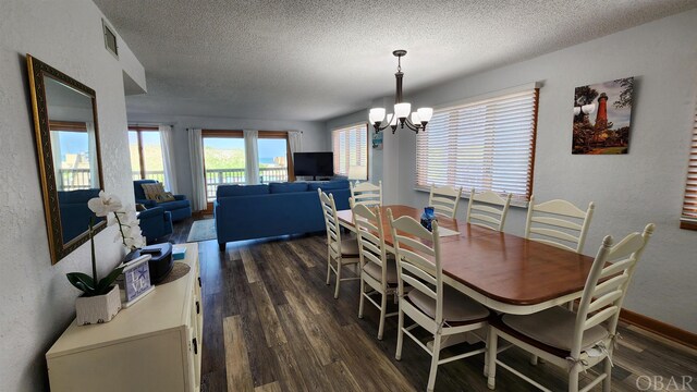 dining room with an inviting chandelier, dark wood finished floors, a textured ceiling, and a textured wall