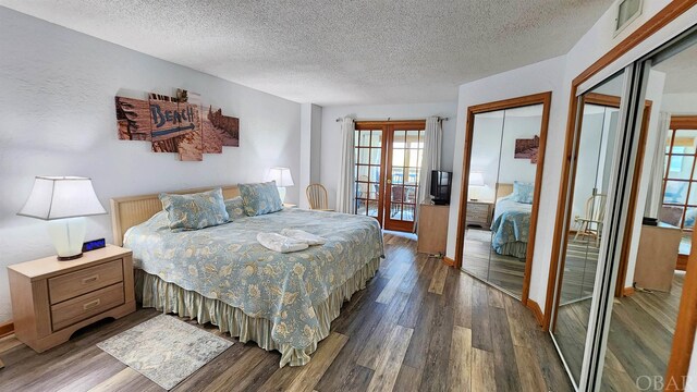 bedroom featuring two closets, a textured ceiling, dark wood-style flooring, and french doors