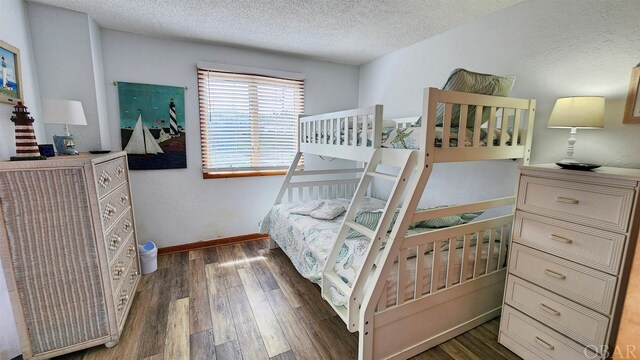 bedroom featuring dark wood finished floors, a textured ceiling, and baseboards