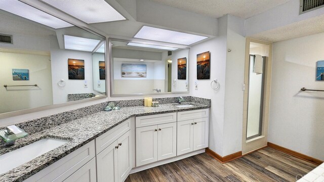 full bathroom featuring wood finished floors, a stall shower, a sink, and visible vents