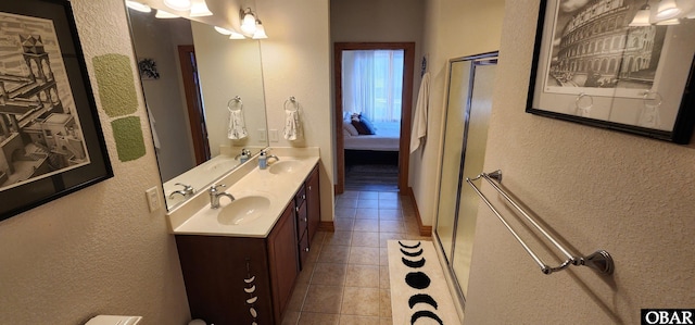 ensuite bathroom featuring double vanity, tile patterned flooring, connected bathroom, and a sink