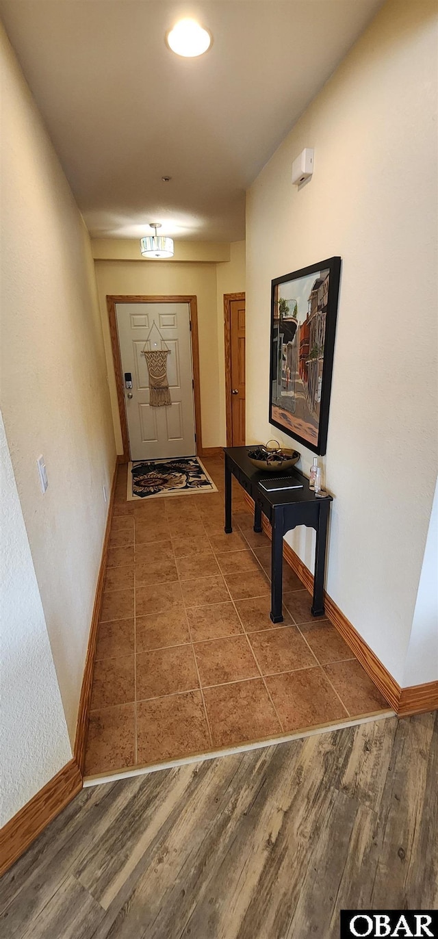 corridor with baseboards and wood finished floors