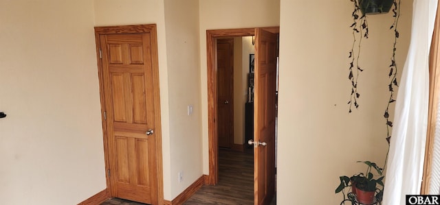 hallway with dark wood-type flooring and baseboards