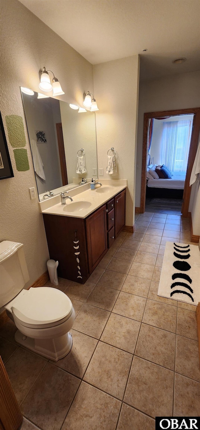 ensuite bathroom with double vanity, toilet, ensuite bath, tile patterned floors, and a sink