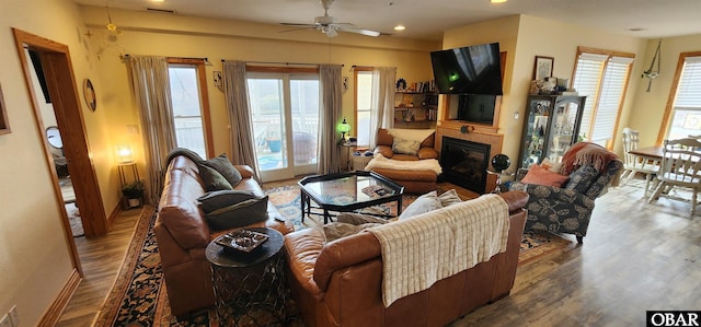 living area with recessed lighting, wood finished floors, visible vents, a ceiling fan, and a glass covered fireplace