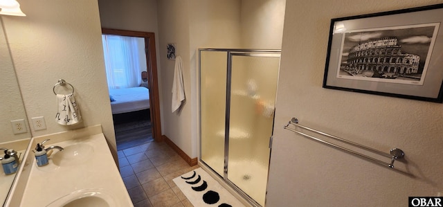 ensuite bathroom with ensuite bathroom, tile patterned flooring, vanity, baseboards, and a shower stall