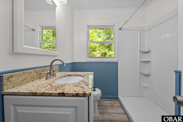 bathroom with a shower, wood finished floors, a wainscoted wall, healthy amount of natural light, and crown molding
