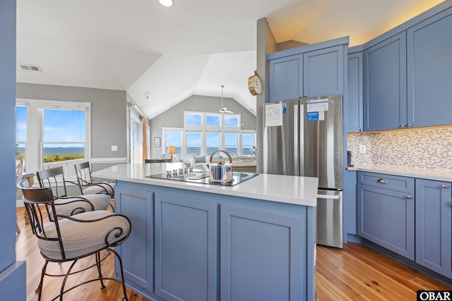 5006 S Links Dr Lot 6, Nags Head, NC 27959 - kitchen featuring black electric stovetop, visible vents, blue cabinets, freestanding refrigerator, and a kitchen bar