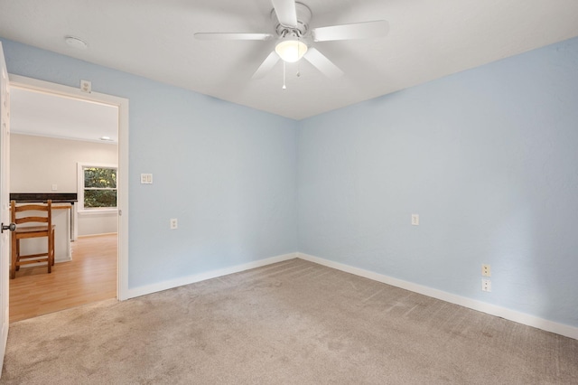 unfurnished room with a ceiling fan, light colored carpet, and baseboards