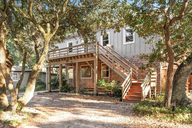 view of front of house with stairway, board and batten siding, and a wooden deck