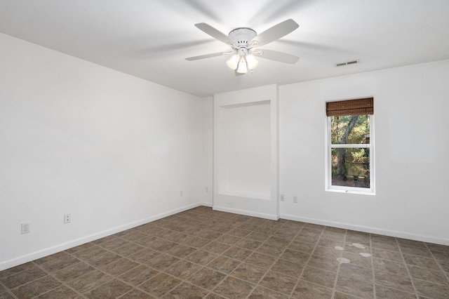 spare room featuring a ceiling fan, visible vents, and baseboards