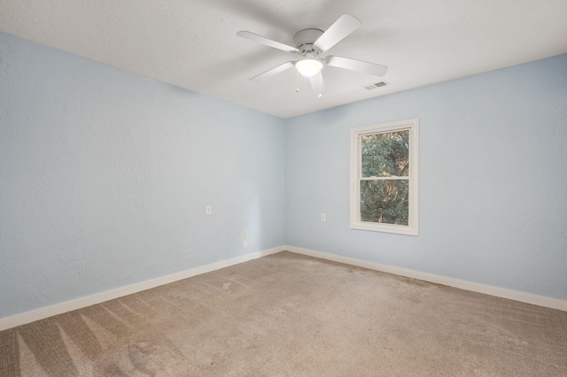 empty room with ceiling fan, carpet floors, visible vents, and baseboards