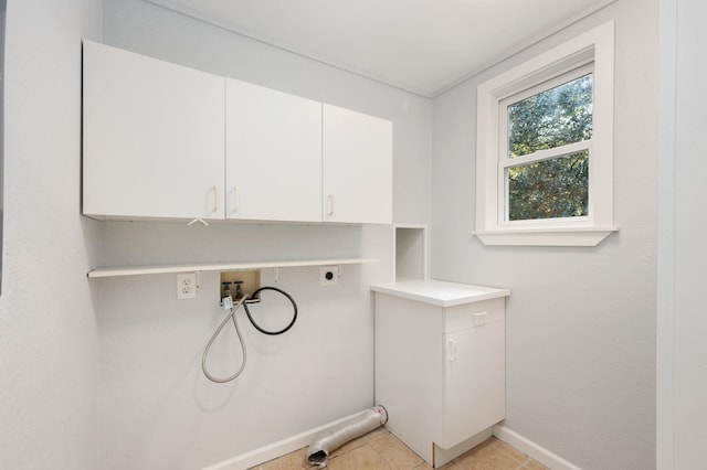 clothes washing area featuring light tile patterned flooring, hookup for an electric dryer, washer hookup, baseboards, and cabinet space