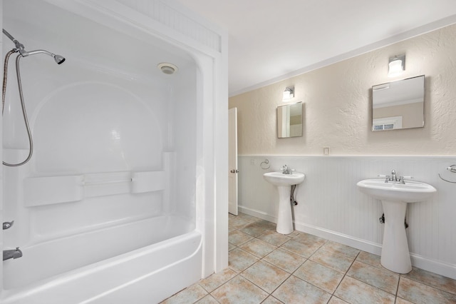 bathroom with tile patterned flooring, bathtub / shower combination, a sink, and a textured wall