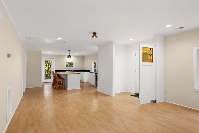 interior space featuring visible vents, open floor plan, white cabinets, a kitchen island, and light wood-type flooring