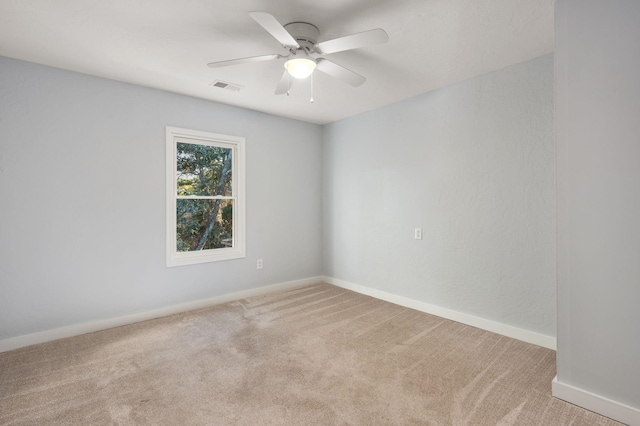 spare room featuring baseboards, a ceiling fan, visible vents, and light colored carpet