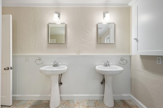 bathroom with a textured wall, a sink, and tile patterned floors