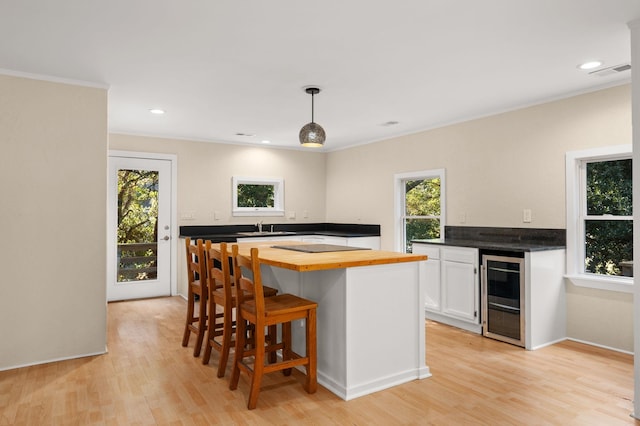 kitchen with light wood-style floors, pendant lighting, white cabinetry, and a healthy amount of sunlight