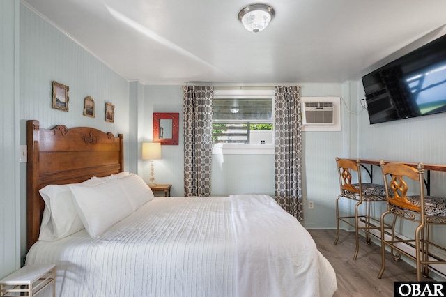 bedroom featuring a wall mounted AC and wood finished floors